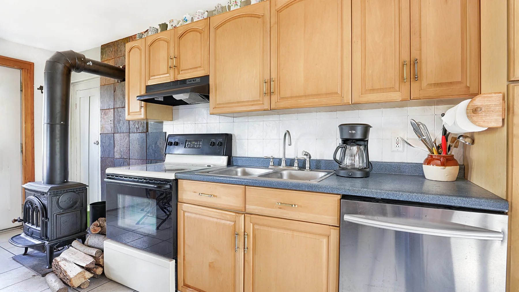 A kitchen with wooden cabinets, a stove, and a sink.