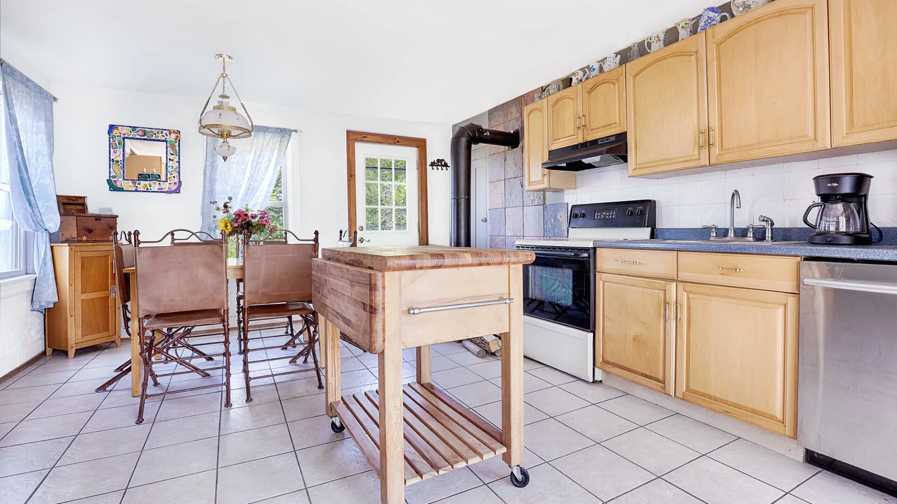 A bright kitchen with wooden cabinets, a central island, and a dining table.