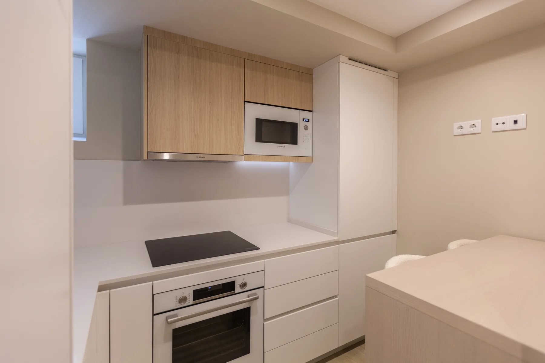 A compact kitchen with wood cabinets, a cooktop, and an oven.
