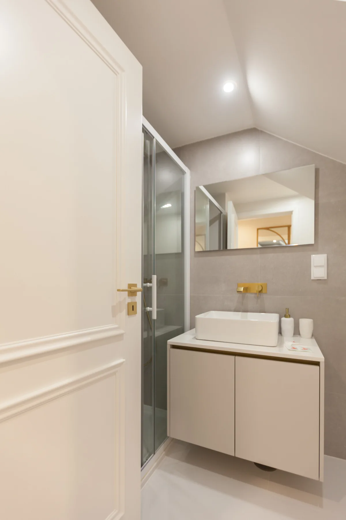 A bathroom with a wall-mounted sink cabinet, mirror, and glass shower.