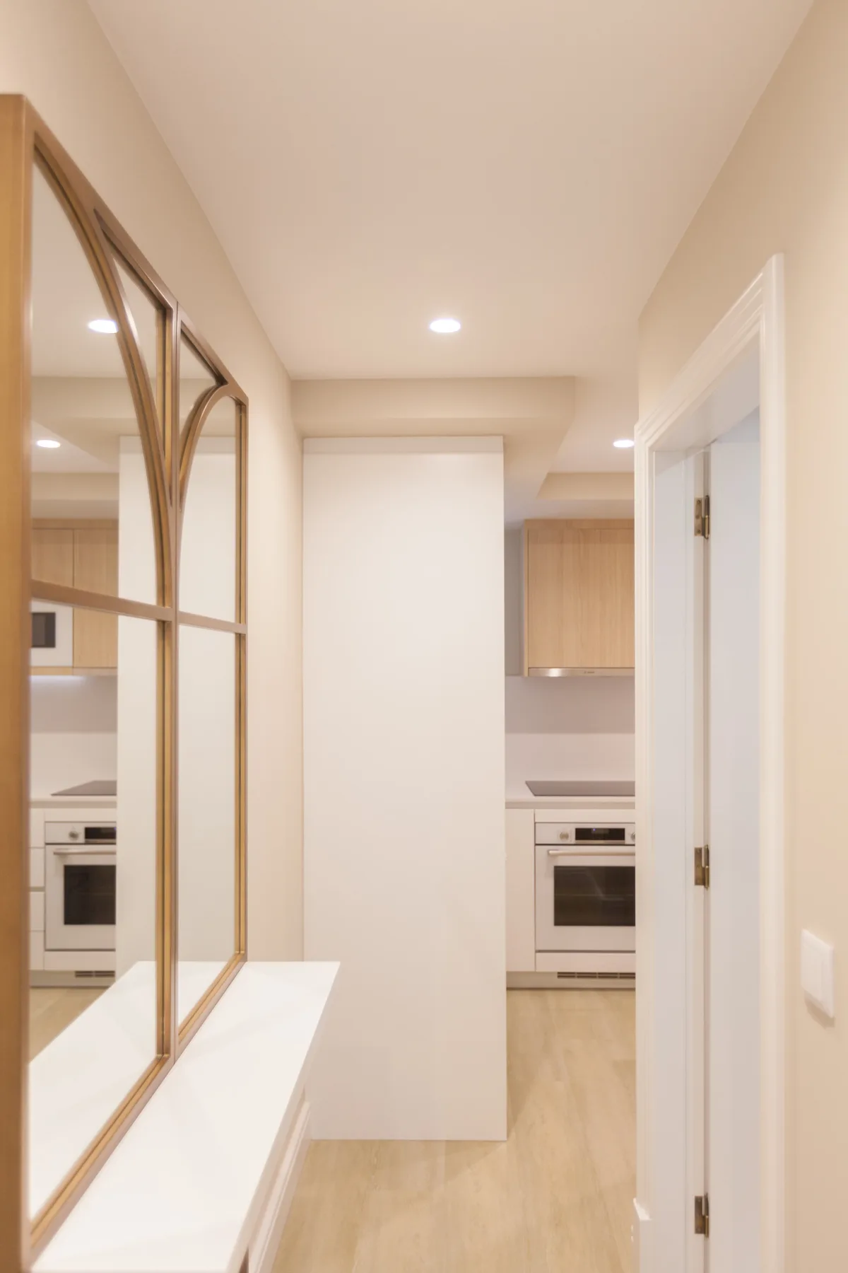 A bright kitchen is visible beyond a narrow hallway with a mirrored wall.