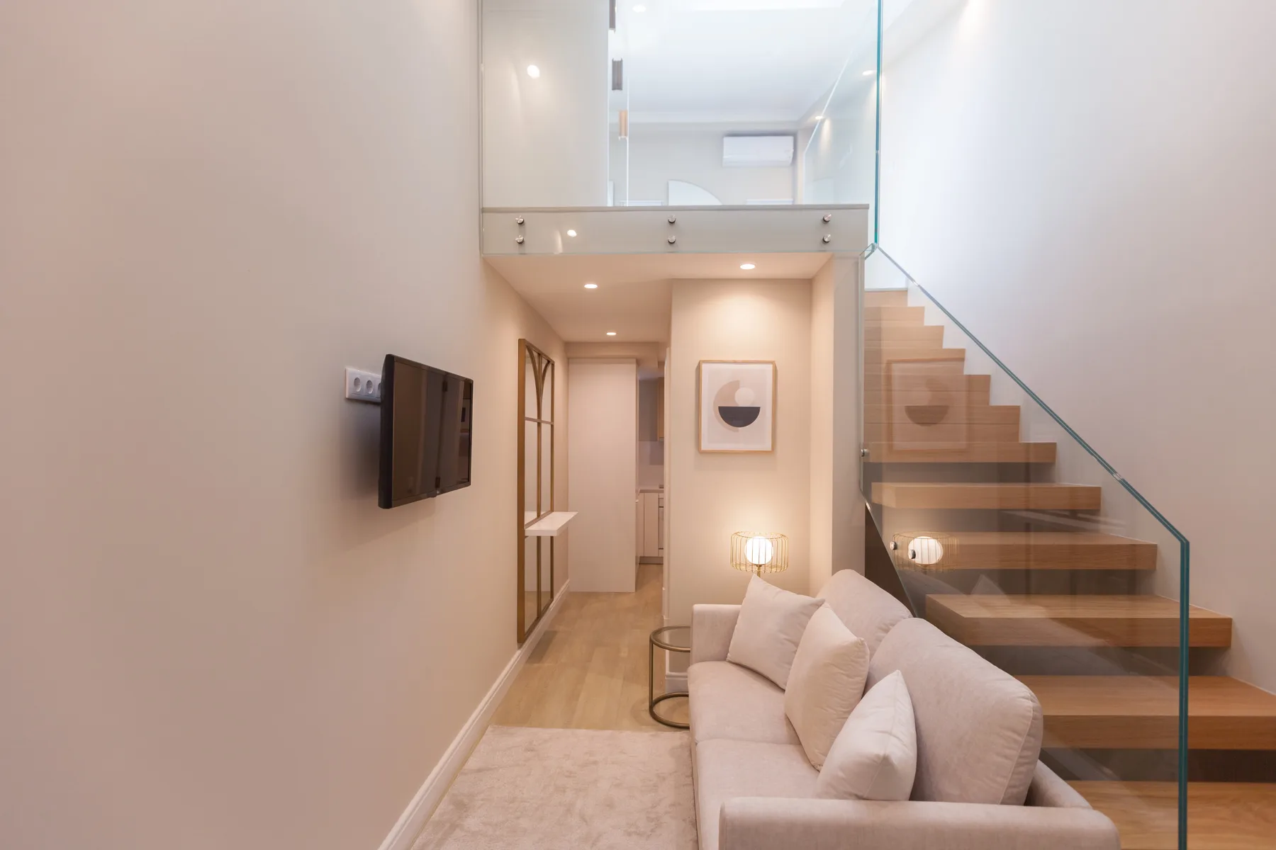 A bright living room with seating beside an open staircase.