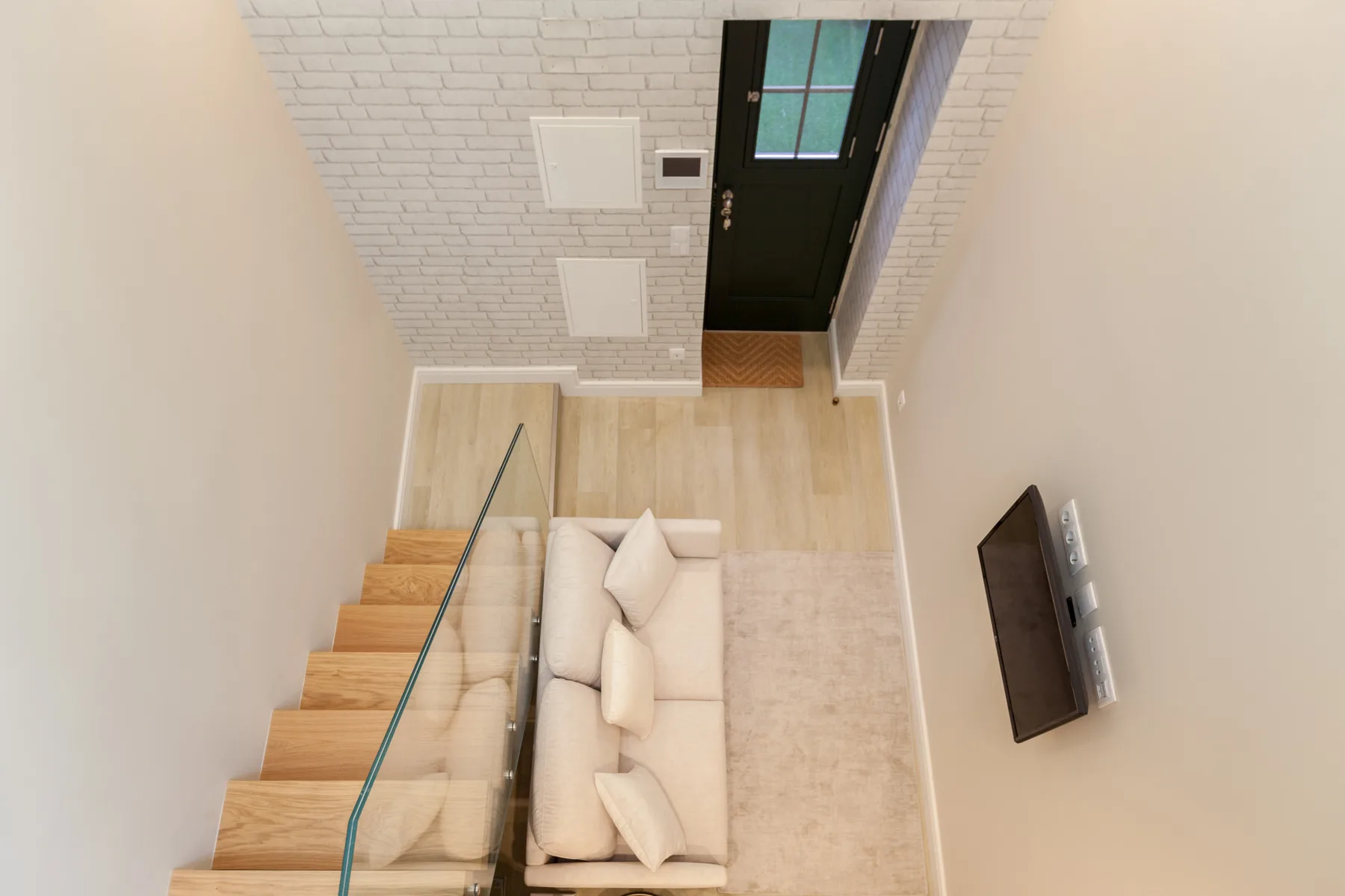 Una sala de estar con asientos junto a una escalera y un televisor en la pared.