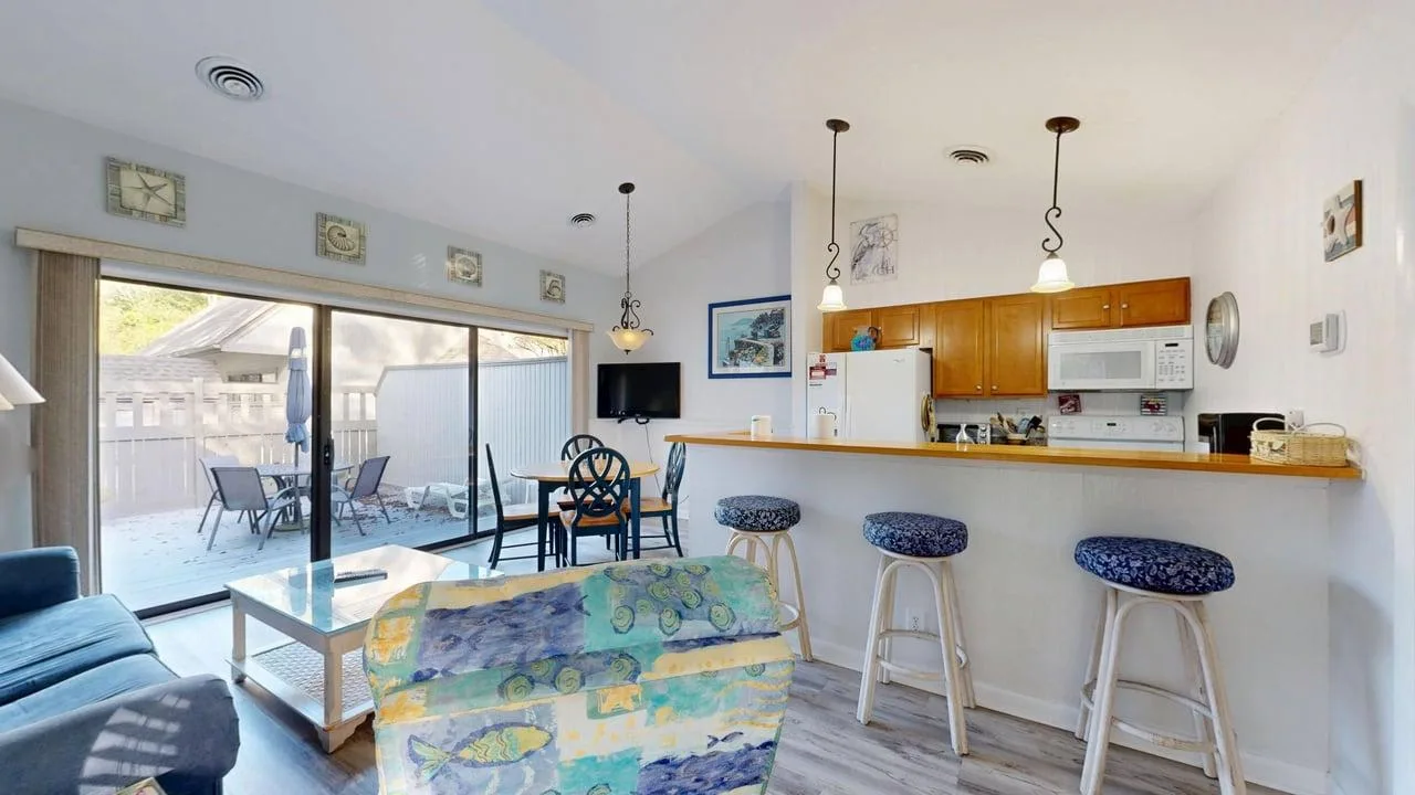 Una sala-comedor abierta con una barra de cocina y puertas al patio.