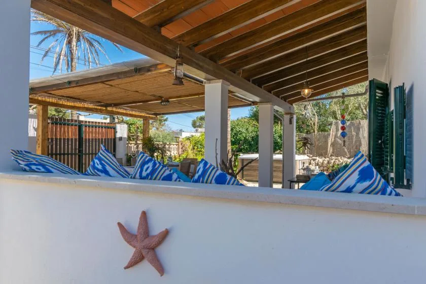 A covered outdoor seating area with striped cushions and a wooden-beam roof.