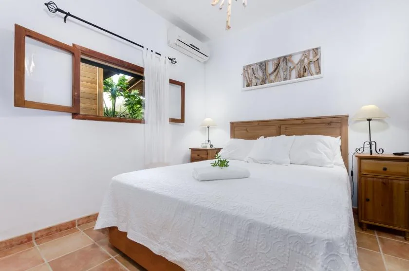 A bright bedroom with a wooden bed, white bedding, and matching bedside tables.