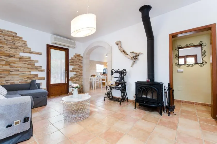 A bright living room with seating, a coffee table, and a freestanding stove.