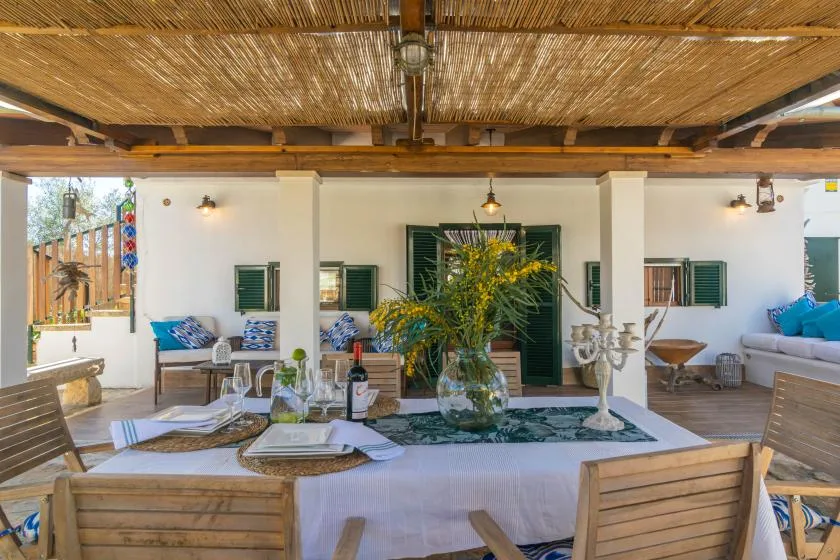 A covered outdoor dining area with a long table and seating.
