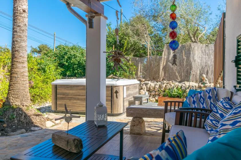 An outdoor patio with a hot tub and cushioned seating.
