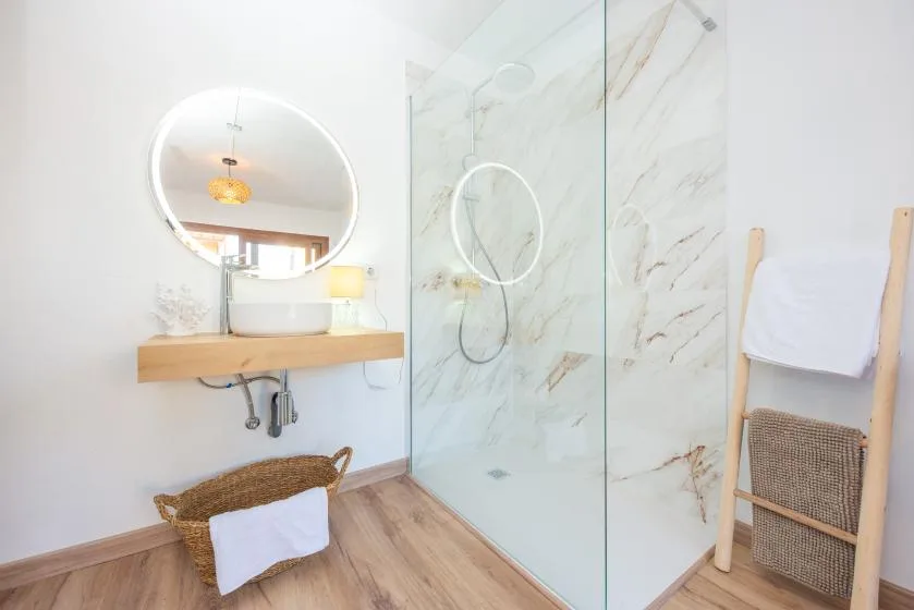 A bright bathroom with a glass shower and a wall-mounted vanity.