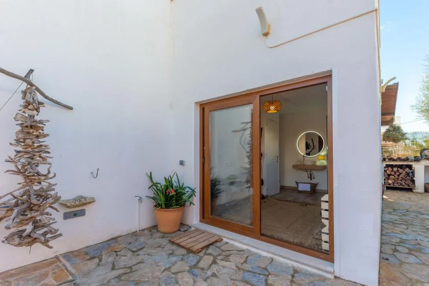 A stone-paved patio outside a white building, with a sliding glass door.
