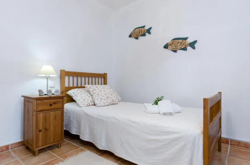 A bedroom with a wooden bed, white bedding, and two fish decorations on the wall.