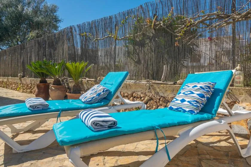 A sunny outdoor patio with turquoise lounge chairs and striped cushions.