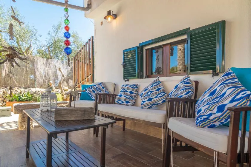 A covered outdoor seating area with patterned cushions and a low table.