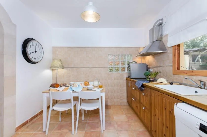 A kitchen with a dining table and wooden cabinets along the counter.