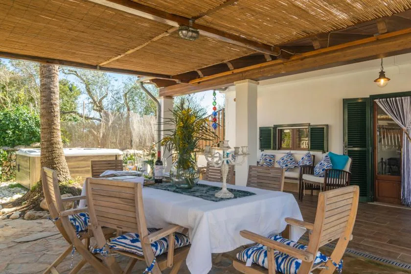 A covered outdoor dining area with a long table and wooden seating.