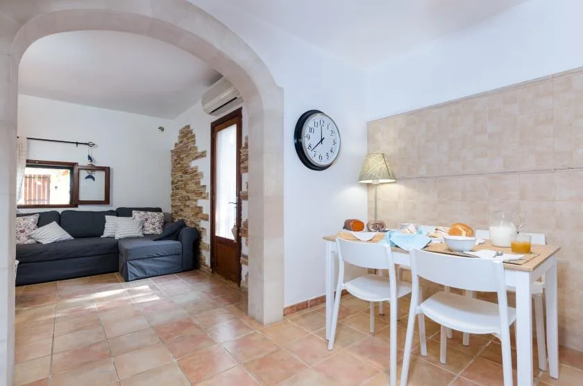 A dining area with a set table beside an arched opening to a living room.