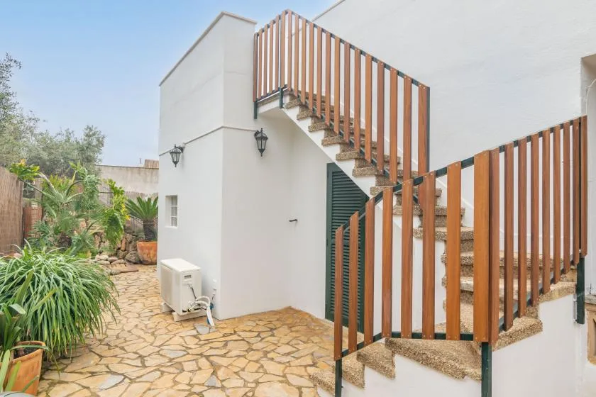 An outdoor courtyard with stone paving, greenery, and an exterior staircase.