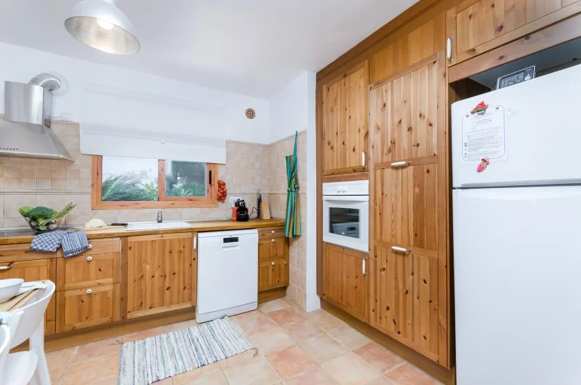 A bright kitchen with wooden cabinets, a countertop, and a refrigerator.