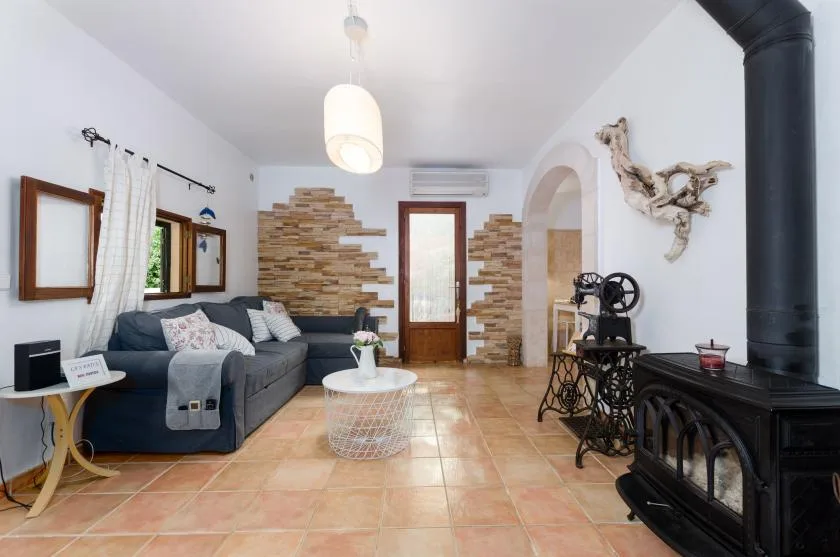 A living room with seating, a tiled floor, and a black freestanding stove.