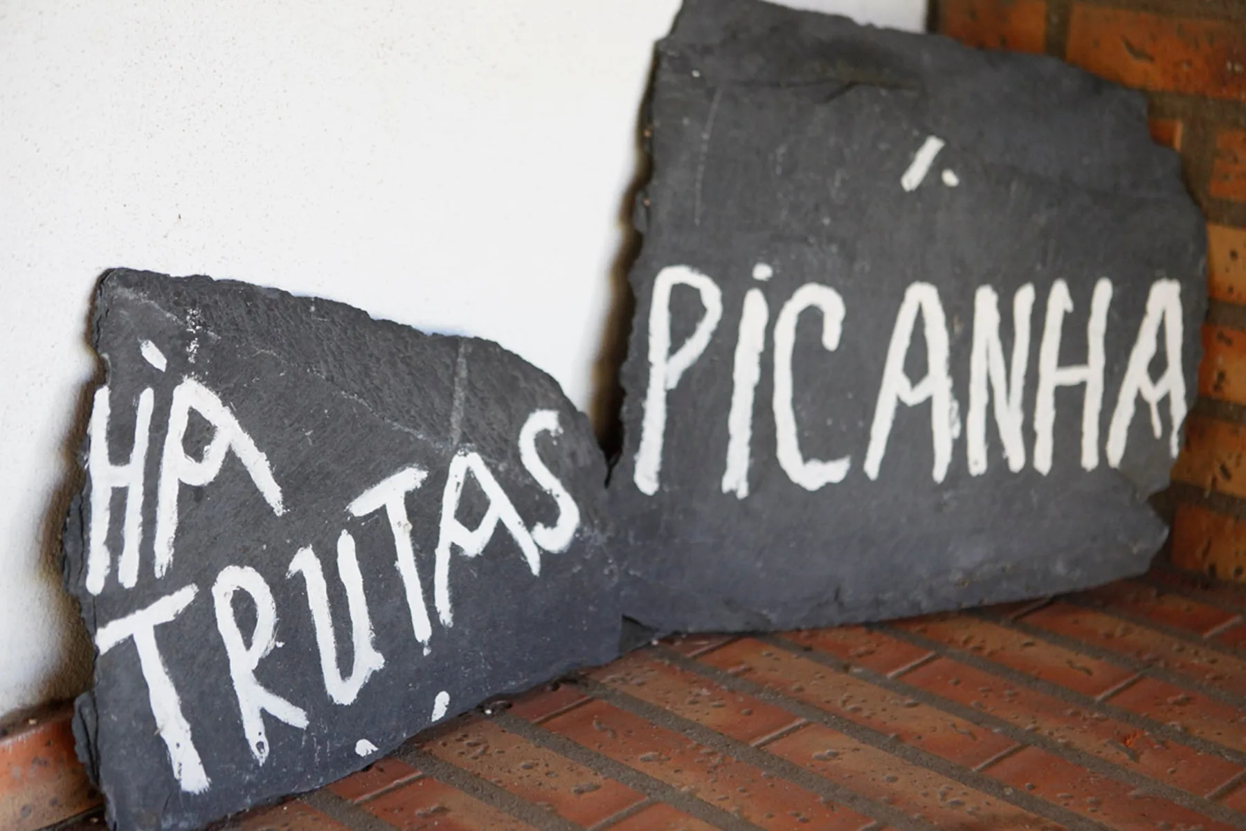 Dark slate signs with white lettering rest on a brick ledge.