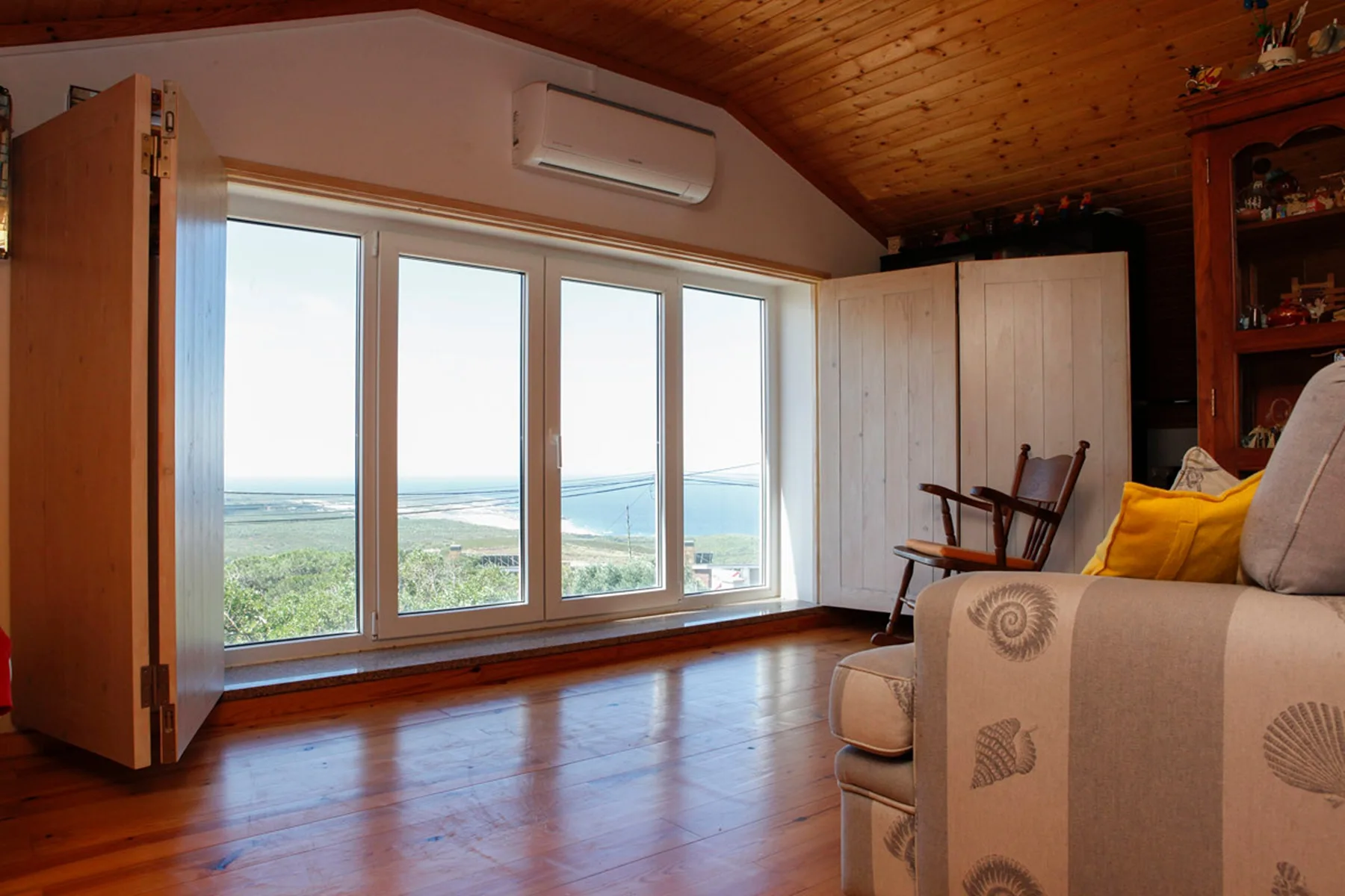 A living room with large windows overlooking the ocean and surrounding landscape.