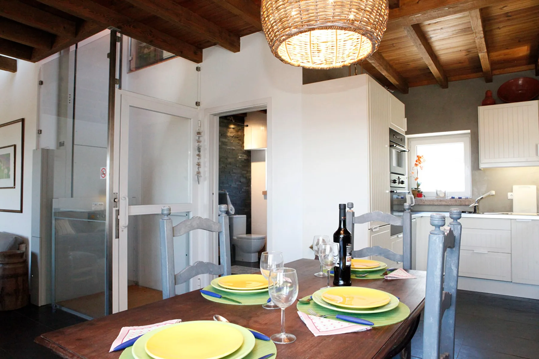 A dining area with a wooden table and place settings beneath exposed ceiling beams.