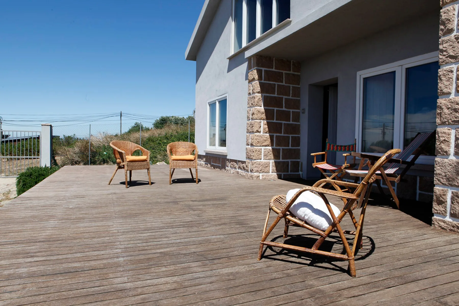 A wooden deck beside the house has outdoor seating and a railing.