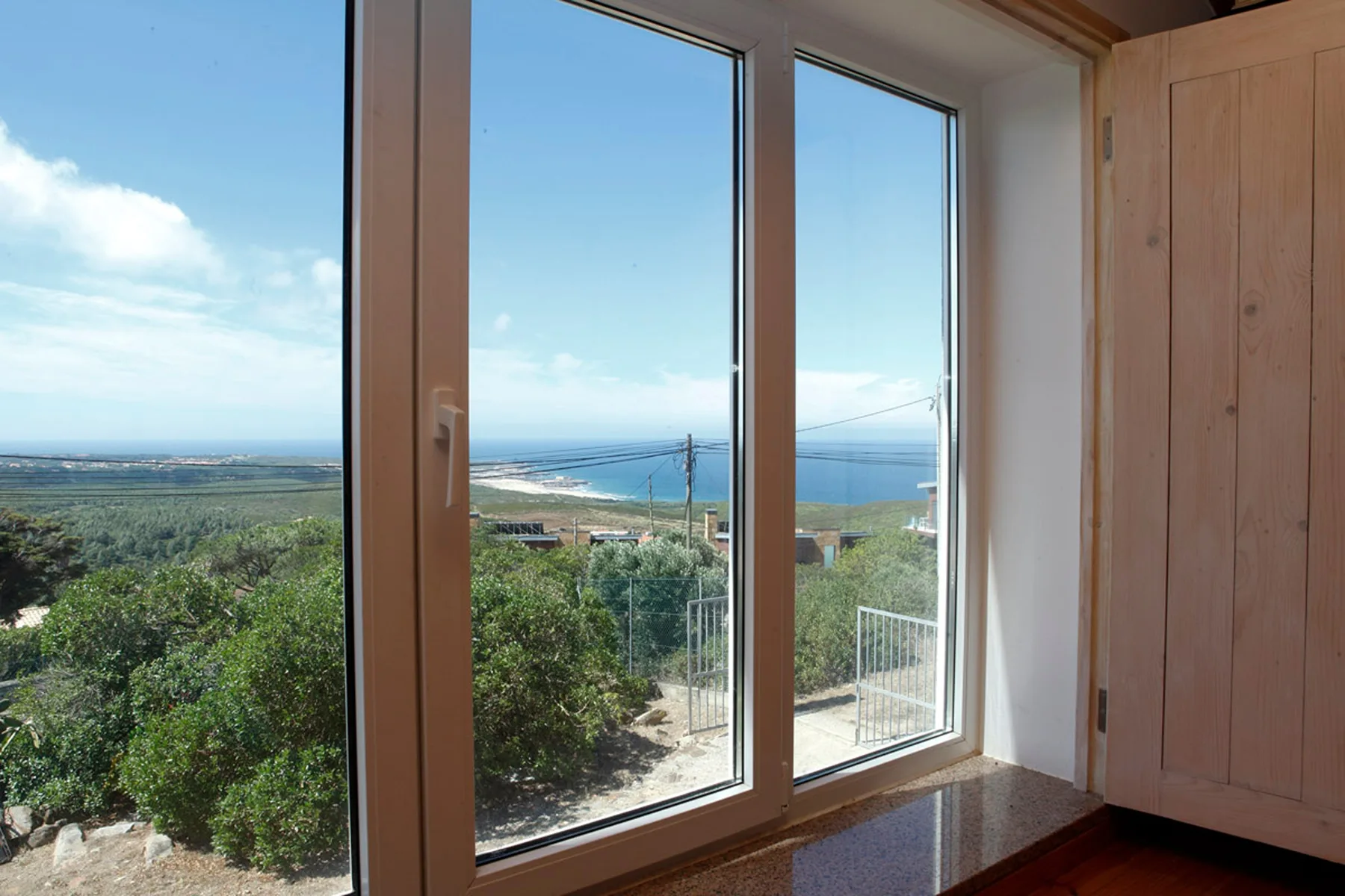 Large windows overlook greenery, coastline, and the sea.