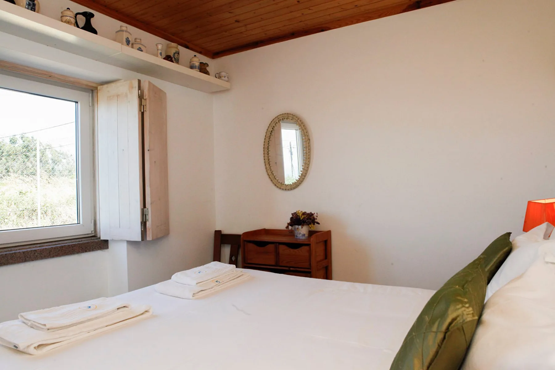 A bedroom with a bed, a window, and a wooden ceiling.