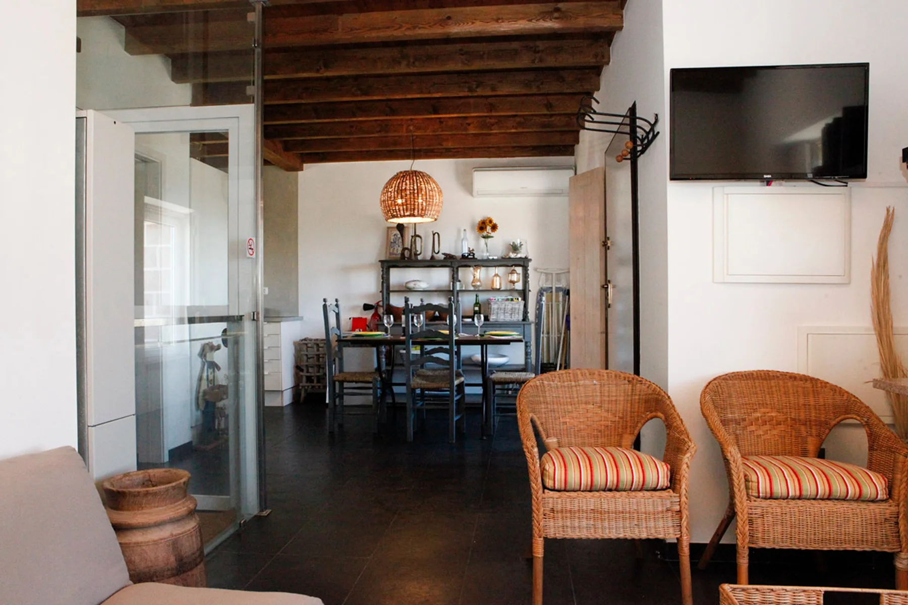 A dining and seating area with a table beneath exposed wooden ceiling beams.