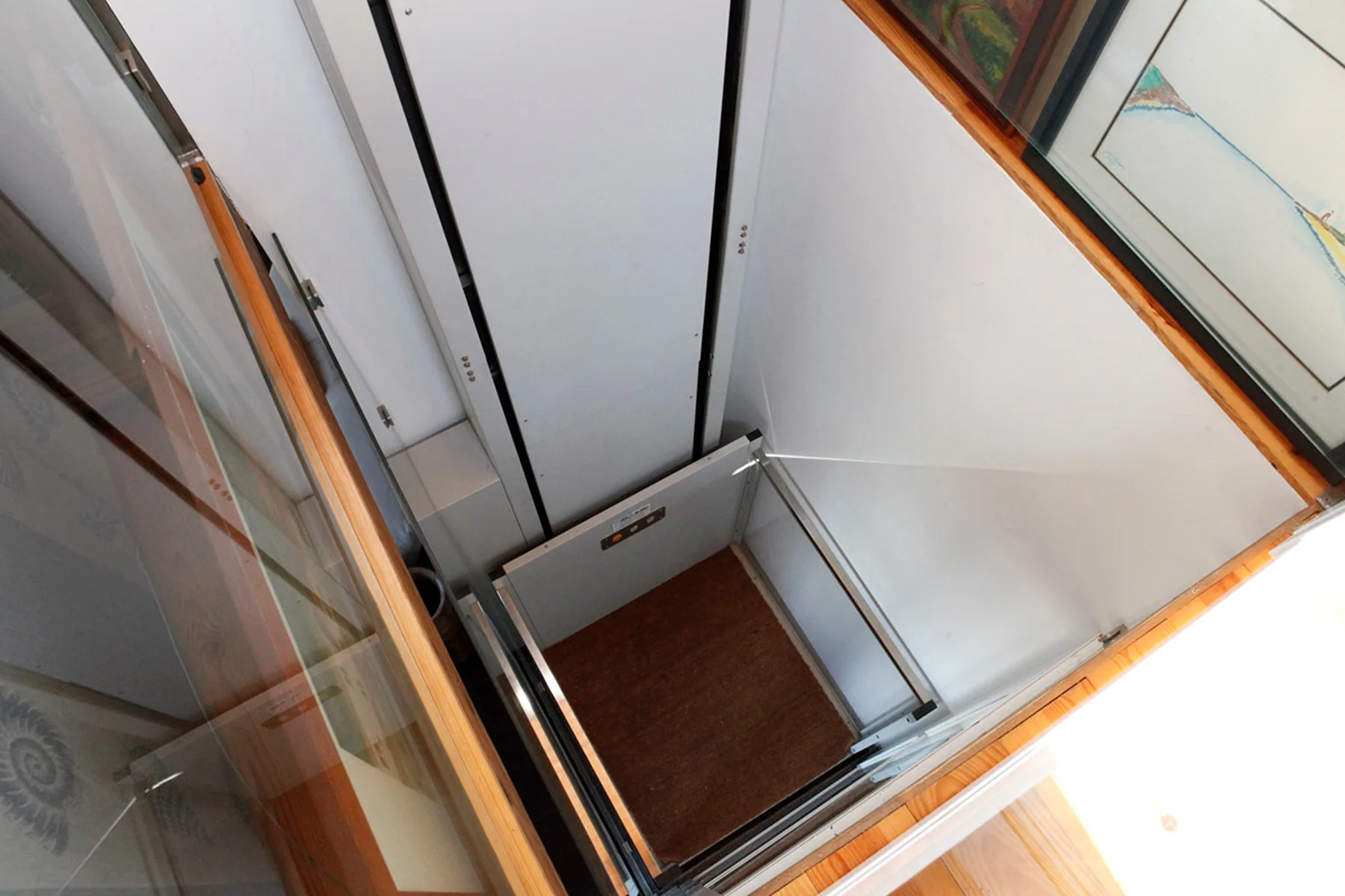 An interior elevator with wood flooring and metal walls.