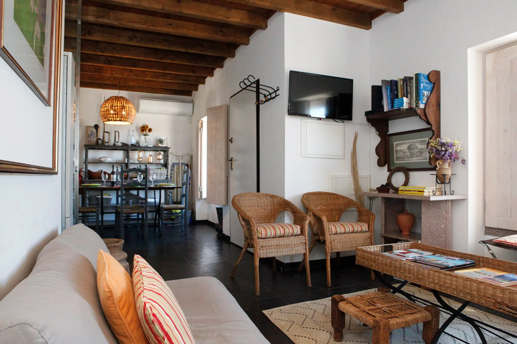 A living room with seating, a television, and a dining area in the background.