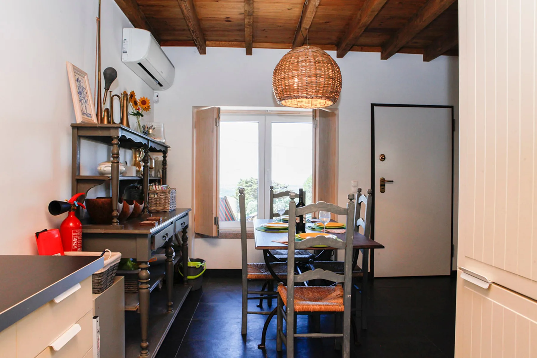 A dining area with a wooden table and chairs beside a bright window.