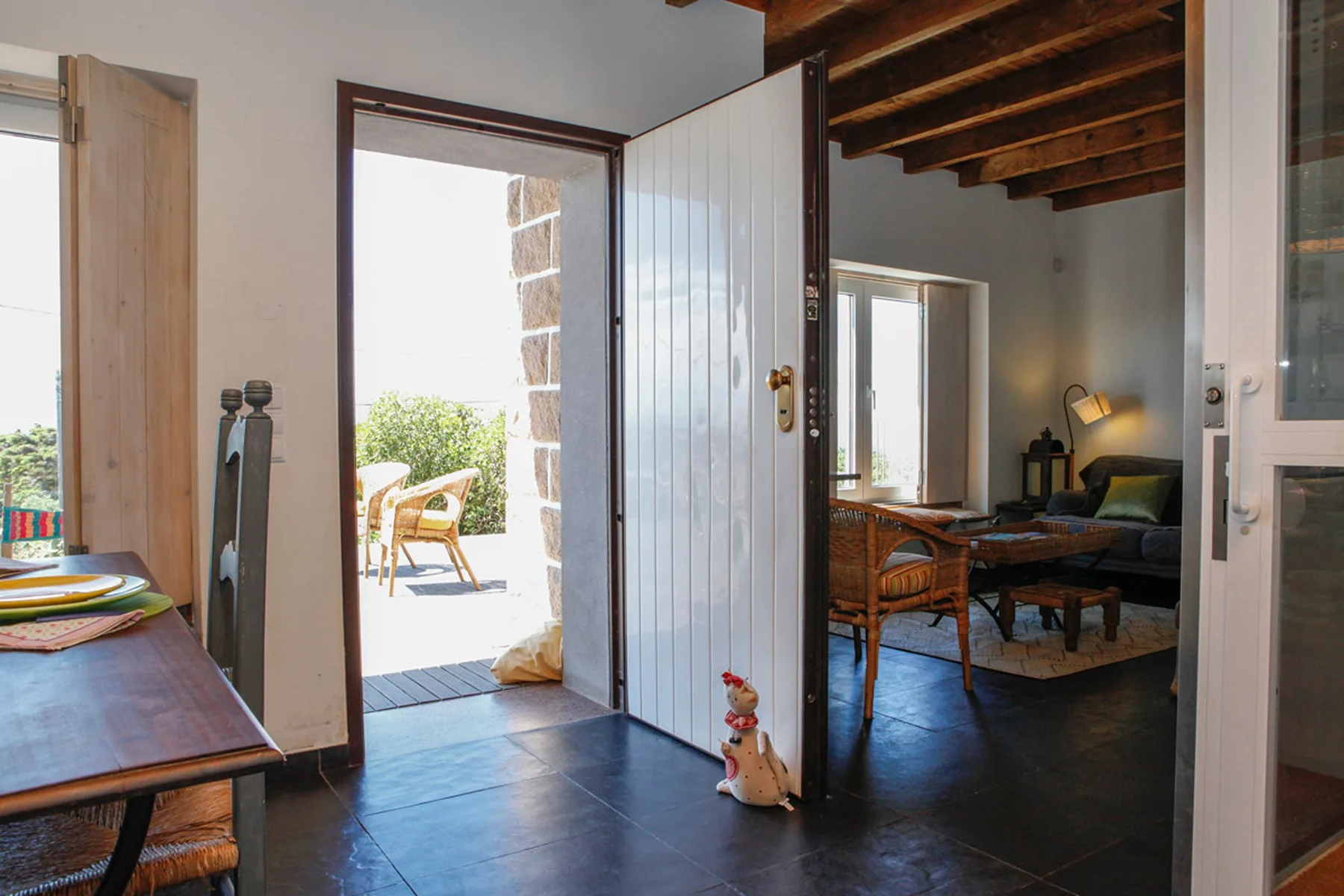 An open doorway leads from a tiled entry area into a living room with seating.