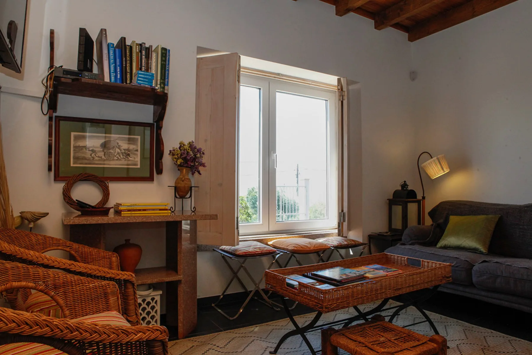 A living room with a wicker seating area, coffee table, and large window.