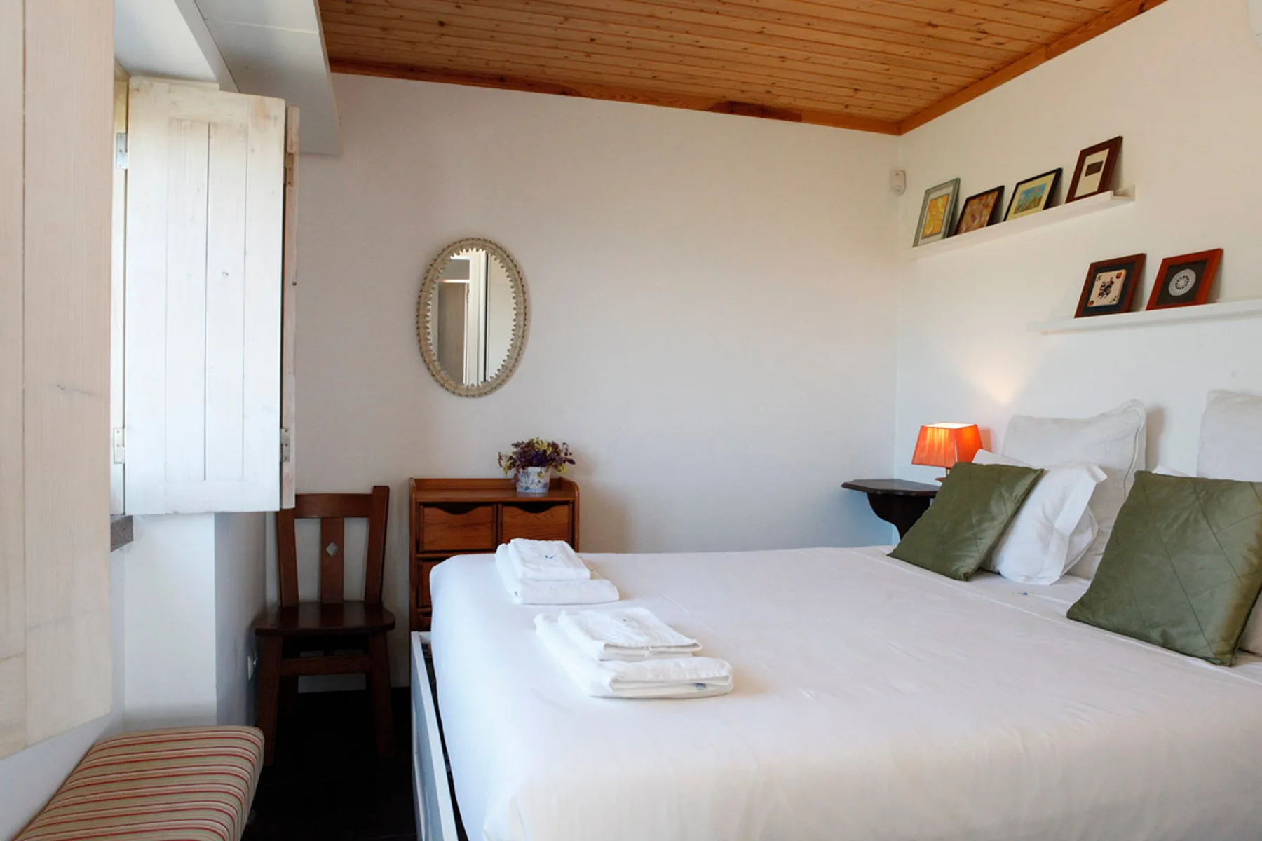 A bedroom with a neatly made bed and a wooden ceiling.