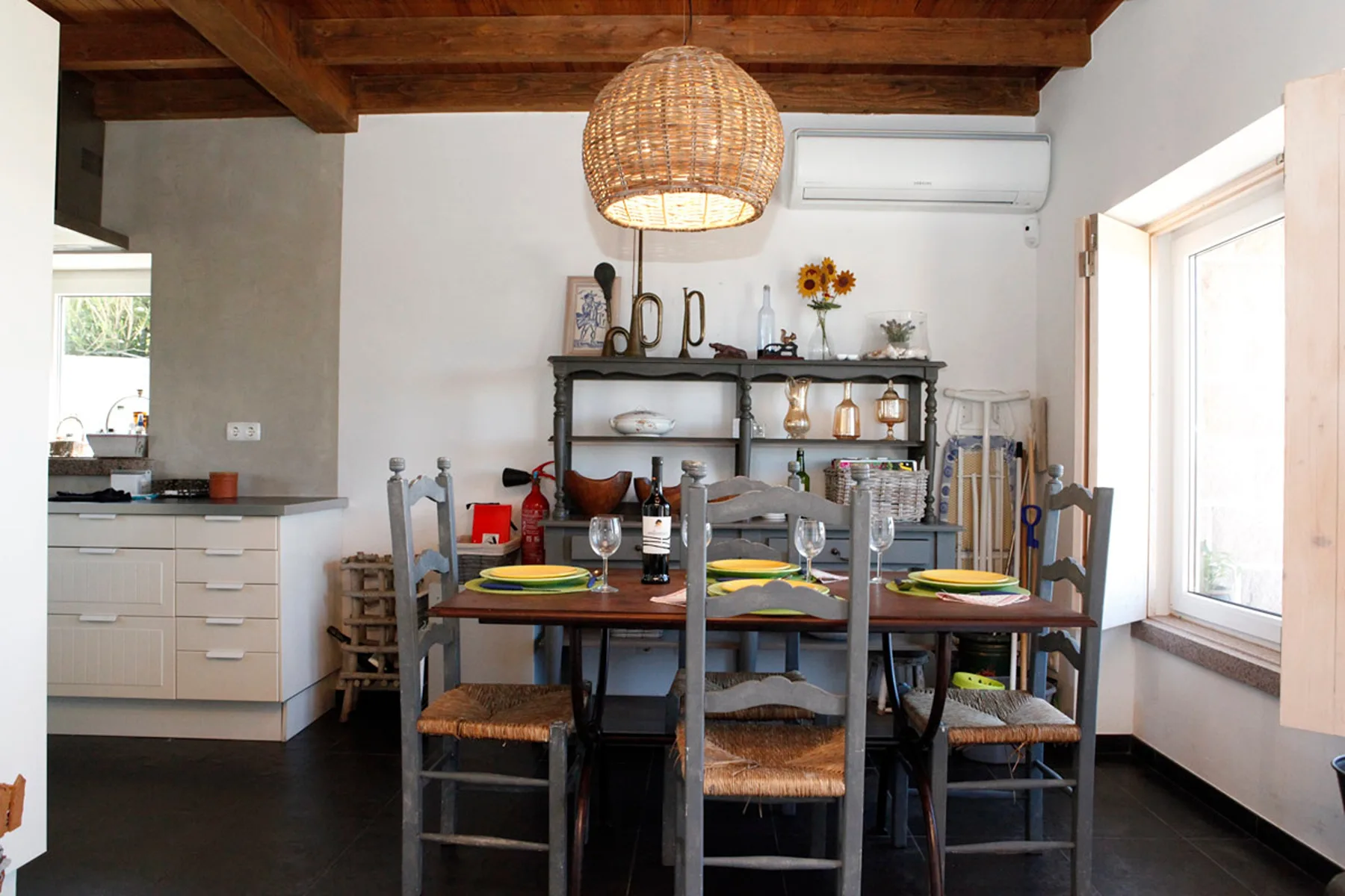 A dining area with a wooden table and chairs beneath exposed ceiling beams.
