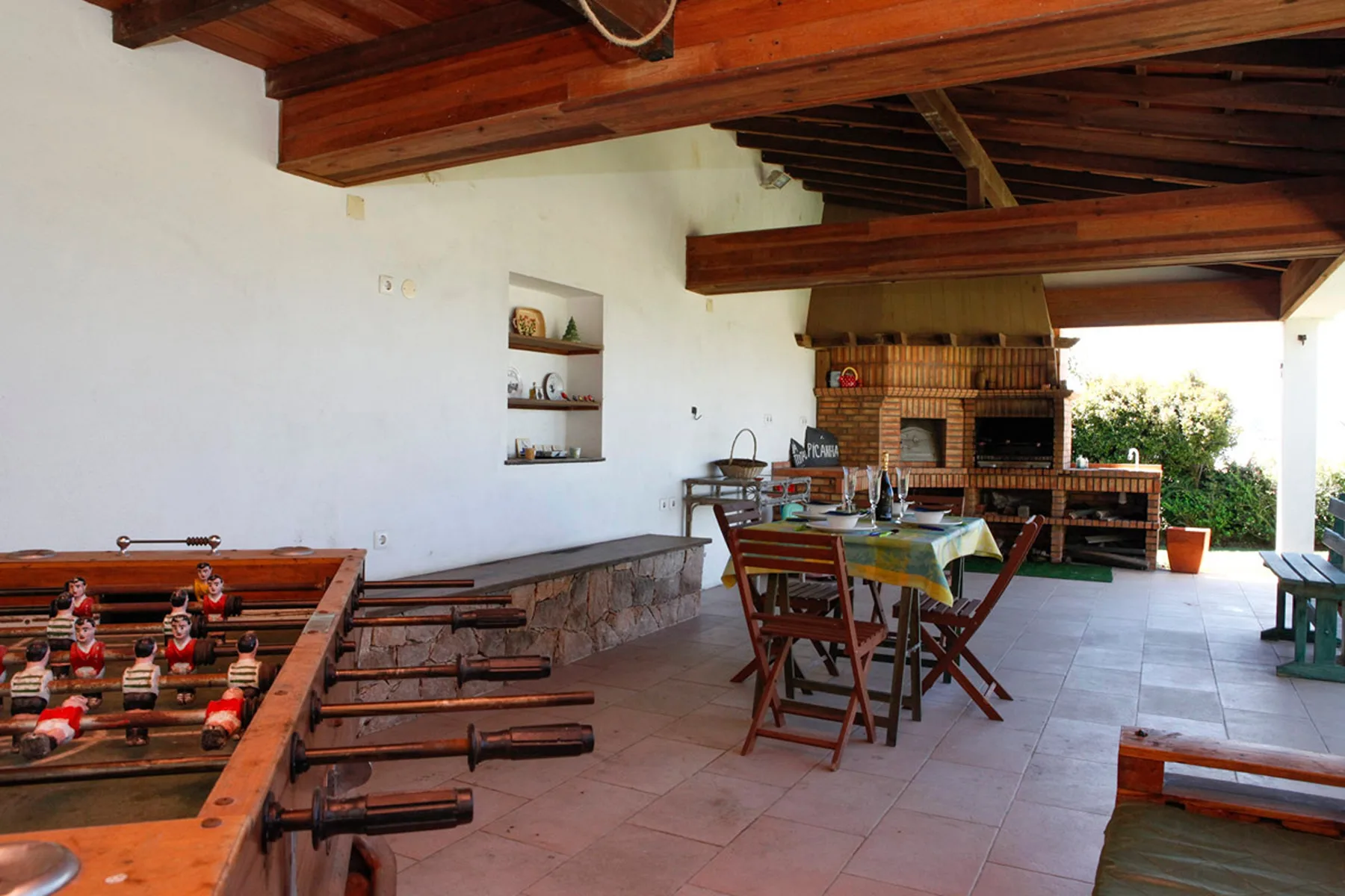 A covered outdoor dining area with a table and foosball table.