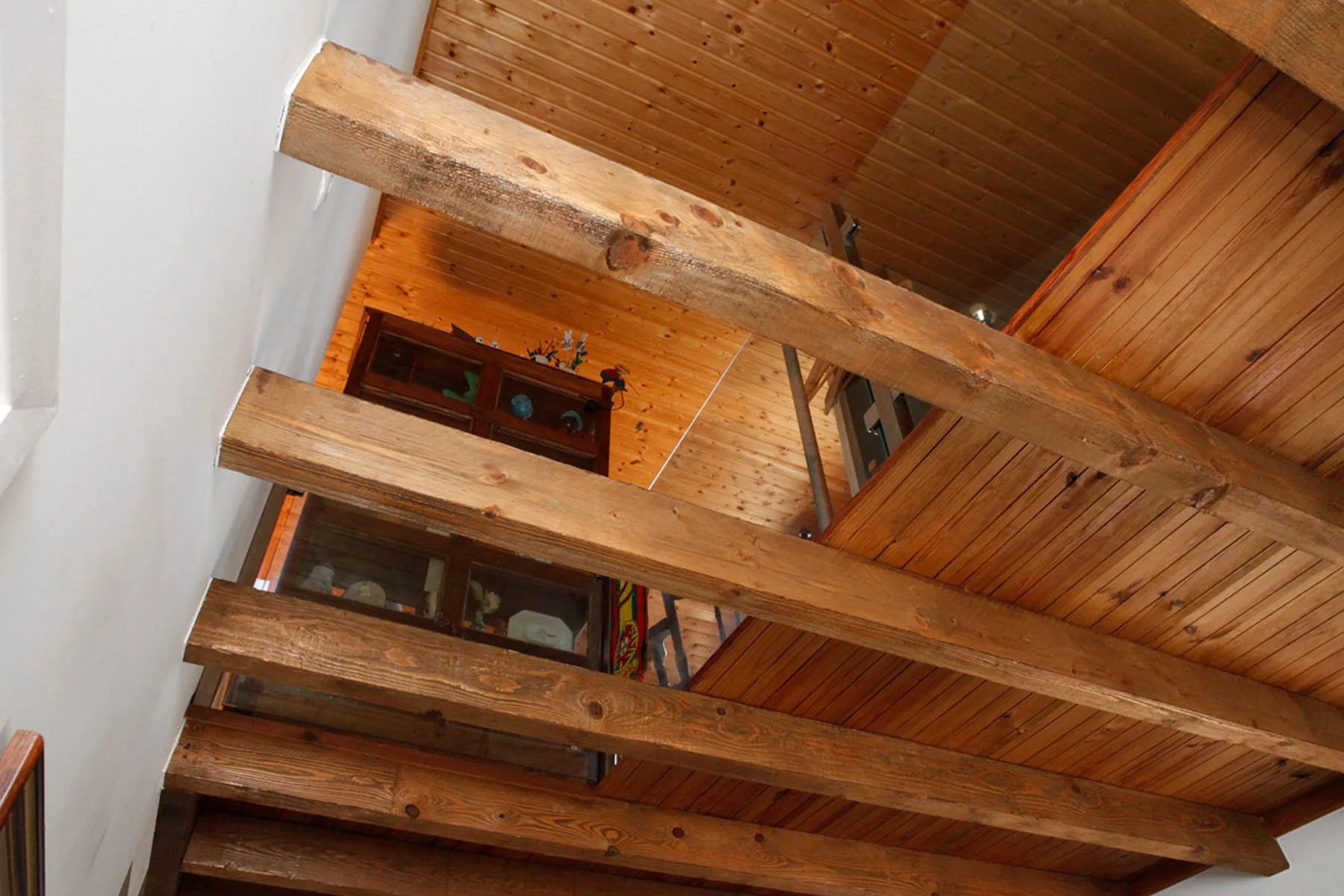 A wooden ceiling with exposed beams overlooks a small interior area.