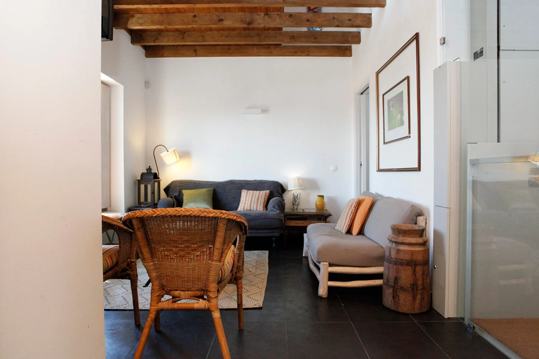A living room with seating, a dining table, and exposed wooden ceiling beams.