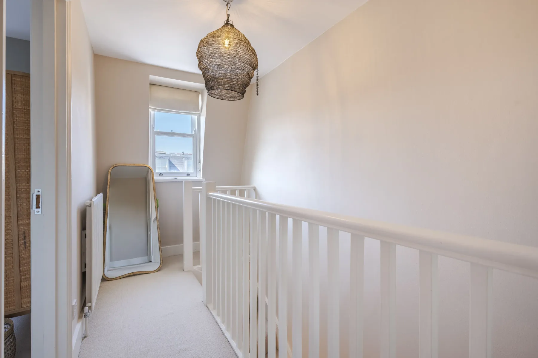 A bright upstairs landing with a white railing and window.