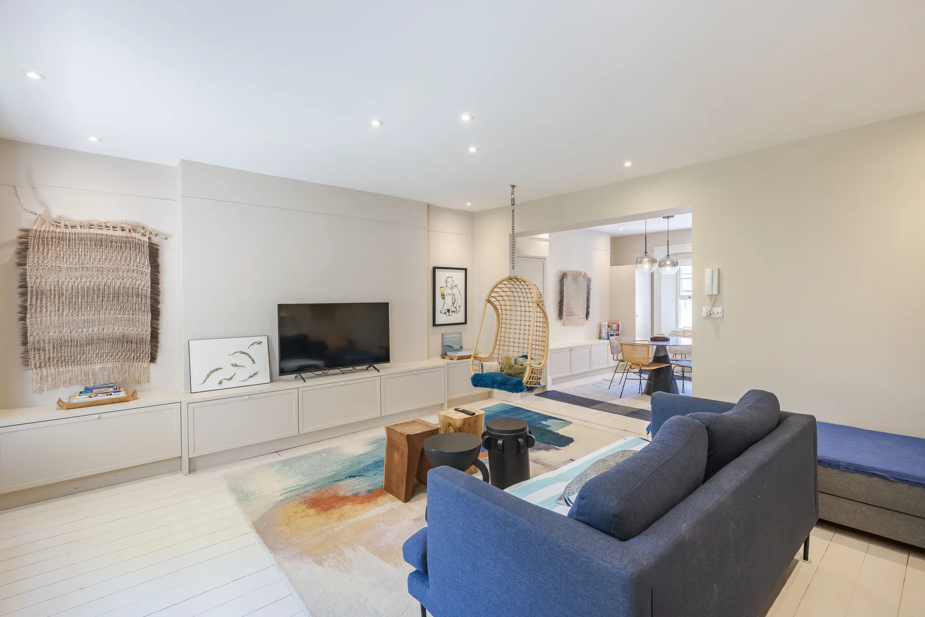 A bright living room with seating, a television, and an adjoining dining area.