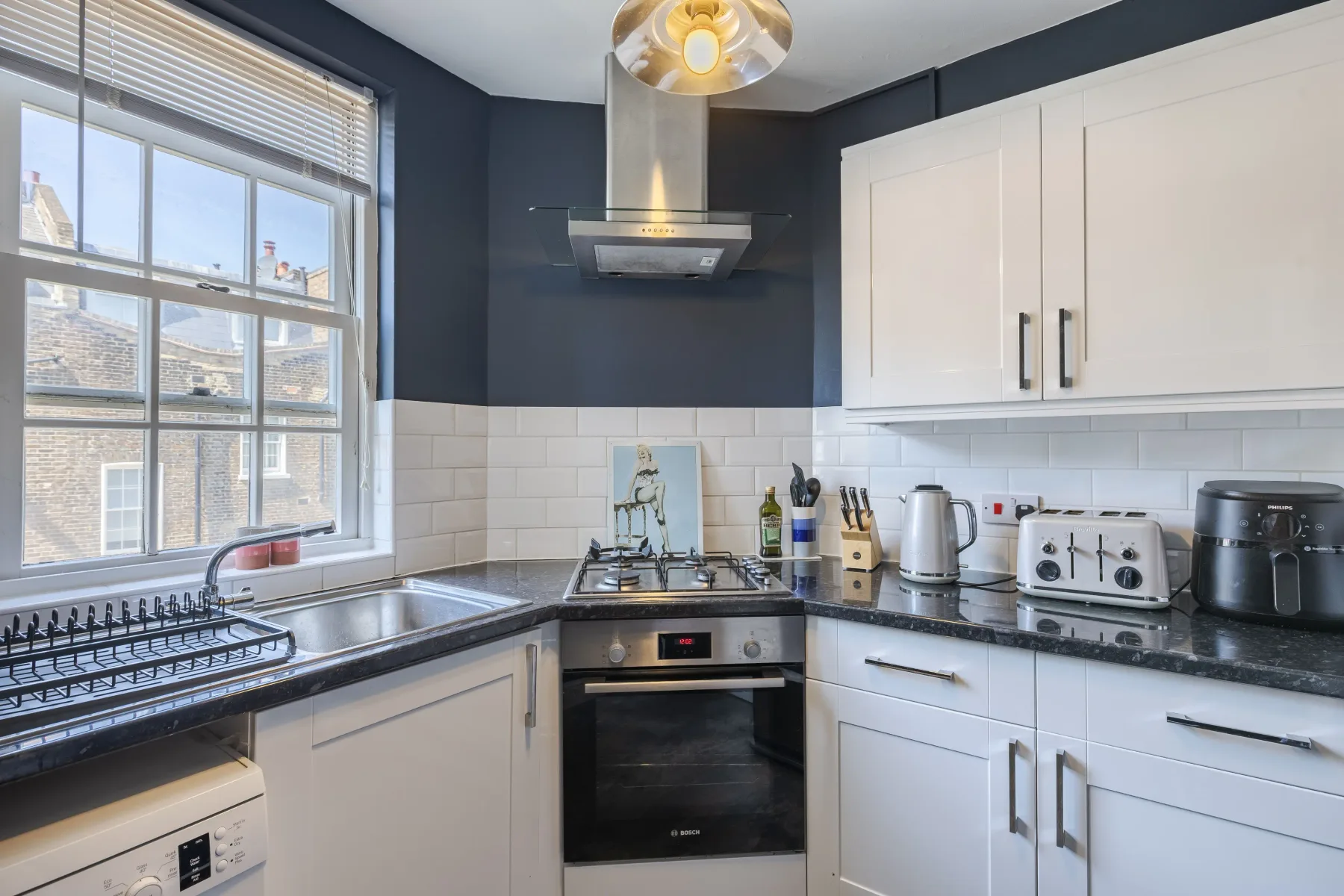 A modern kitchen with white cabinets and a window above the sink.