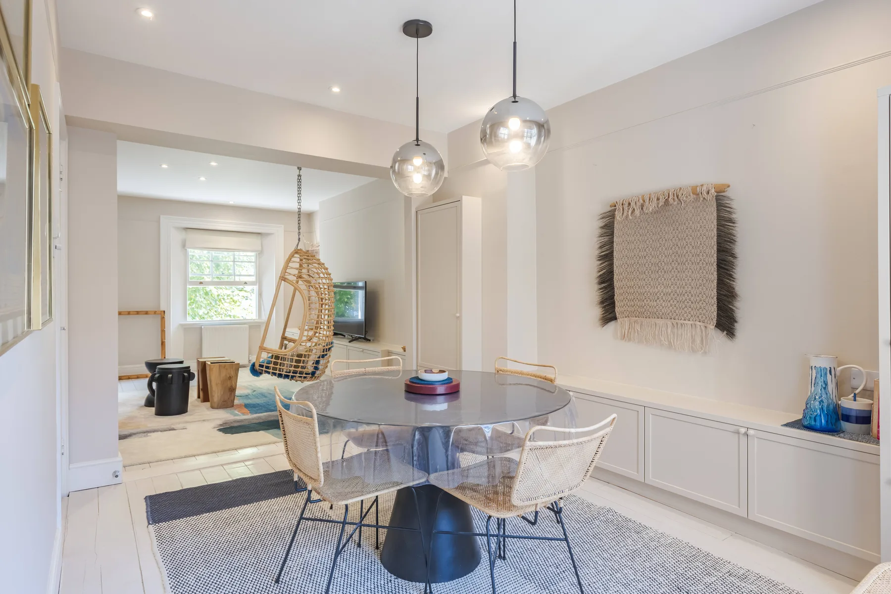 A bright dining area has a round table and woven seating.