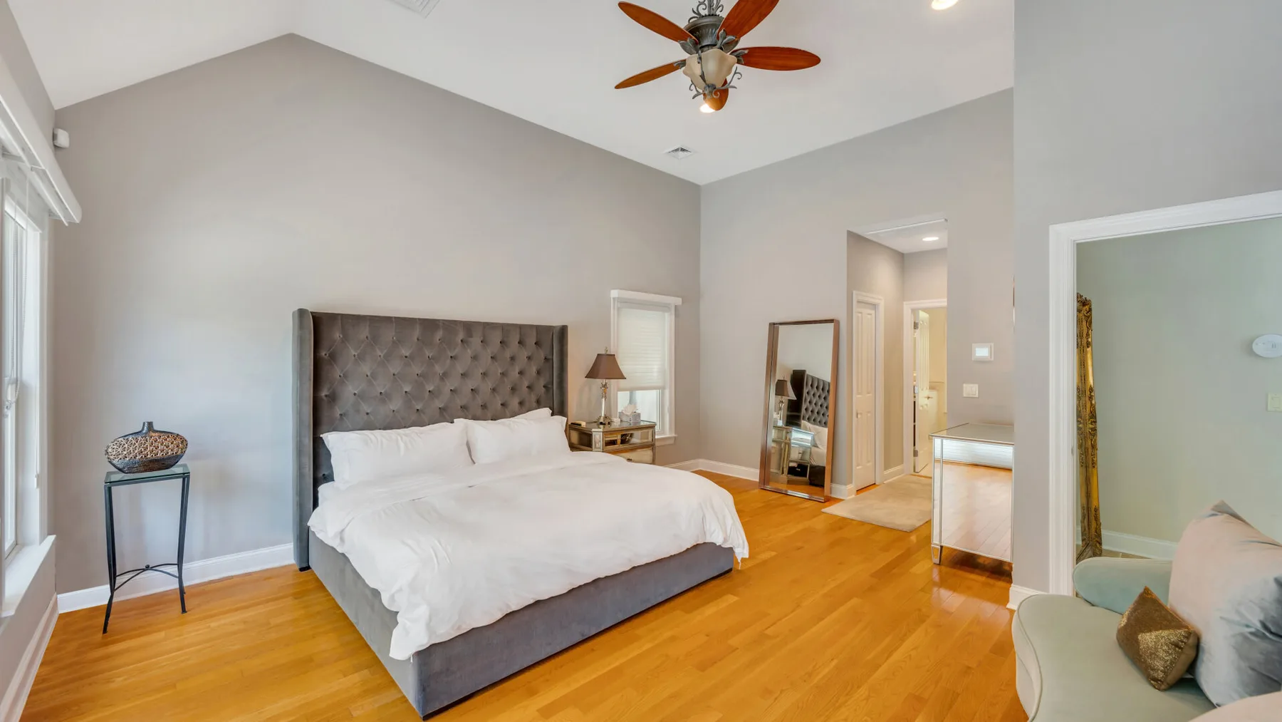 Un dormitorio con una cama grande, piso de madera y un ventilador de techo.