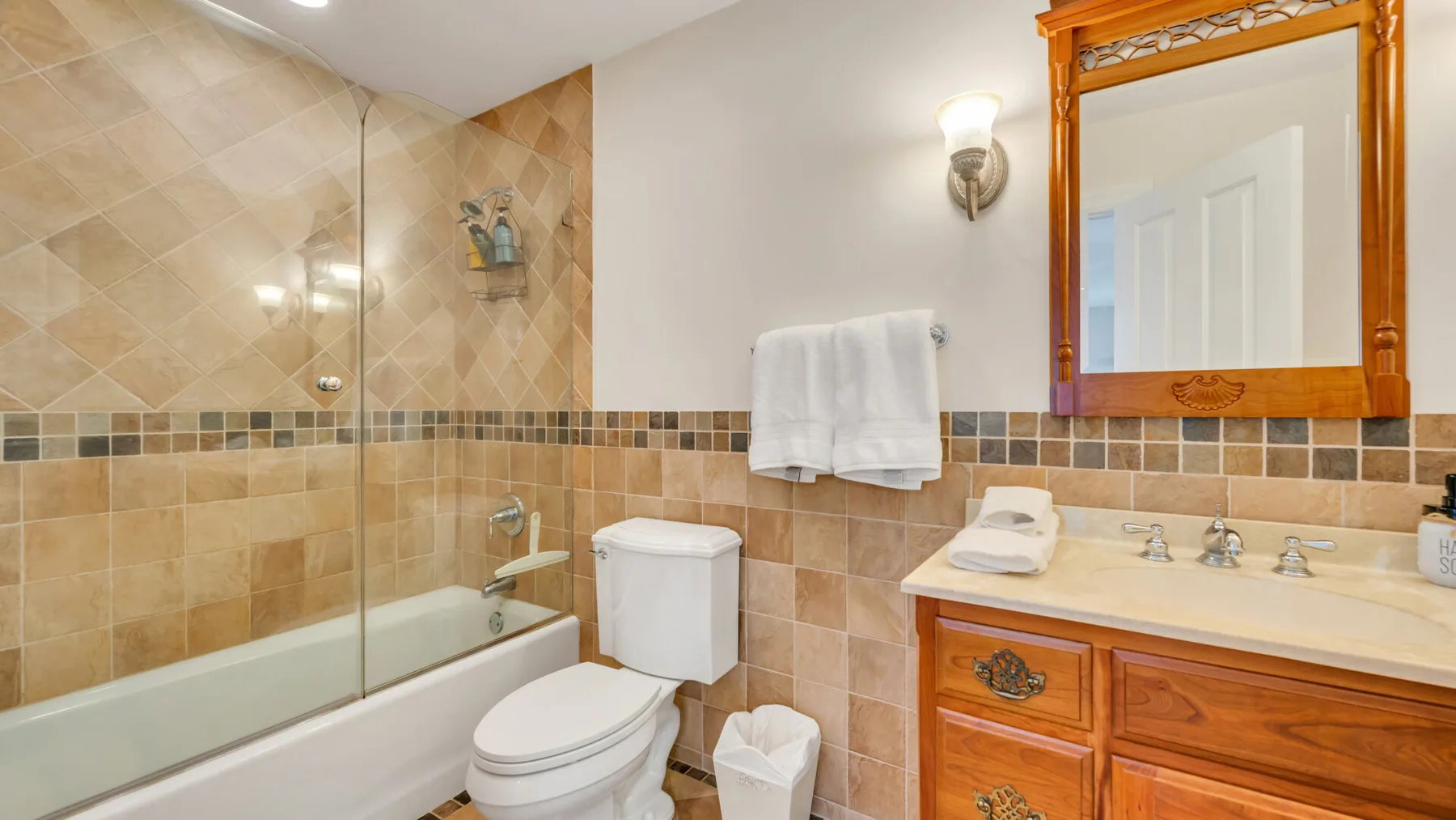 Un baño con bañera alicatada, inodoro y tocador de madera.