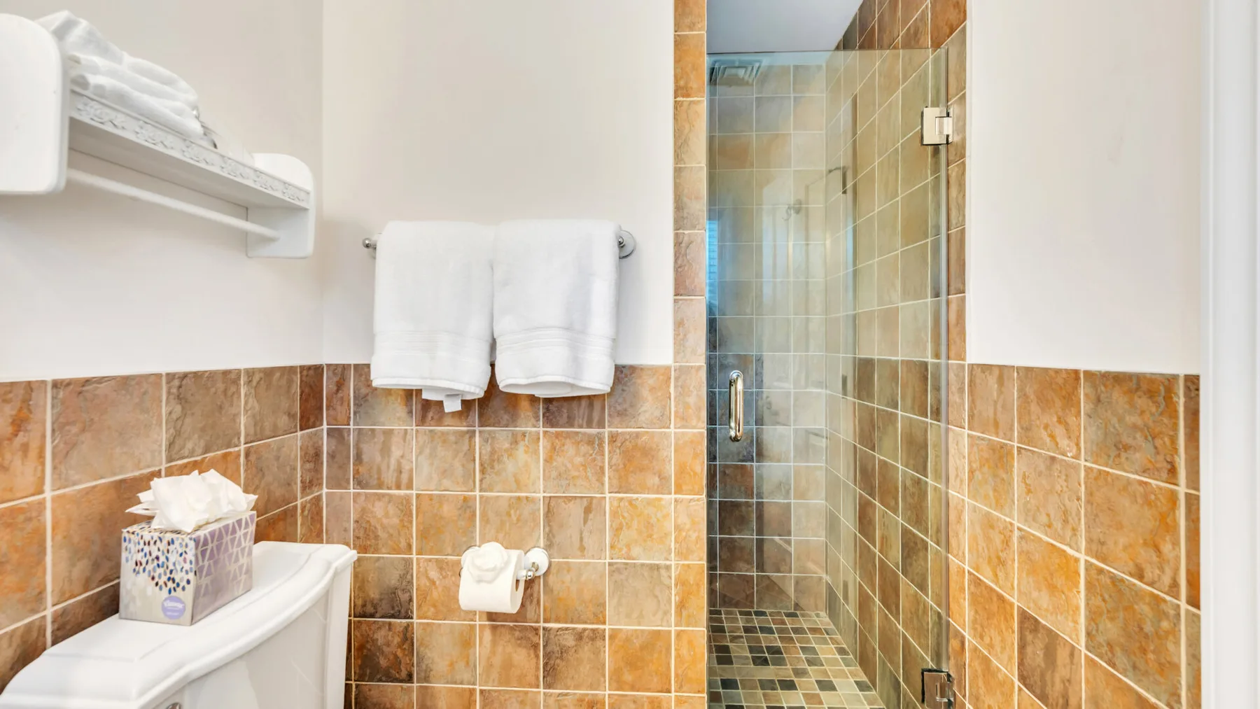 Un baño con azulejos, una ducha de vidrio y toallas.