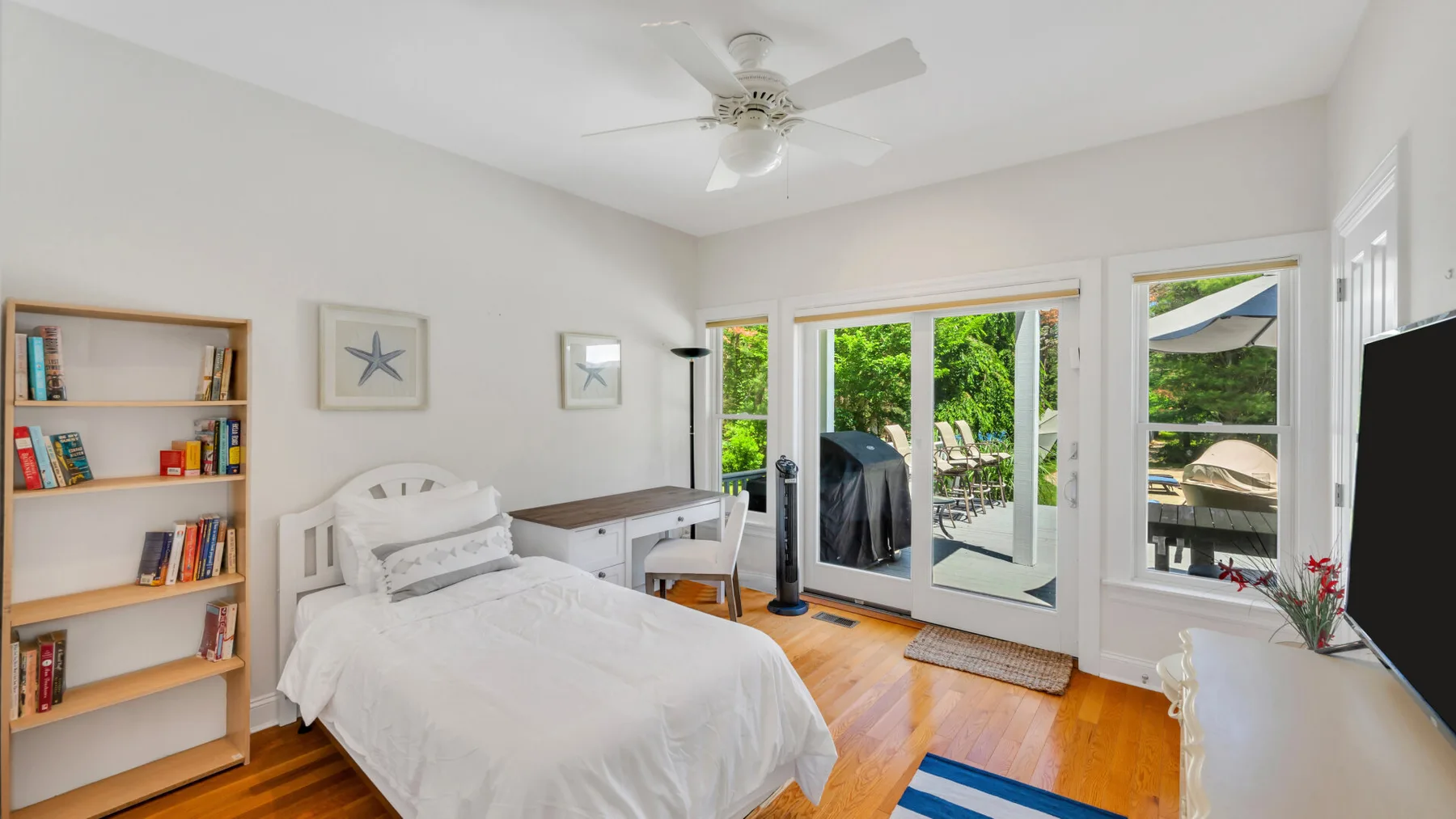 Un dormitorio luminoso con una cama, estanterías y puertas de vidrio que dan a un patio.