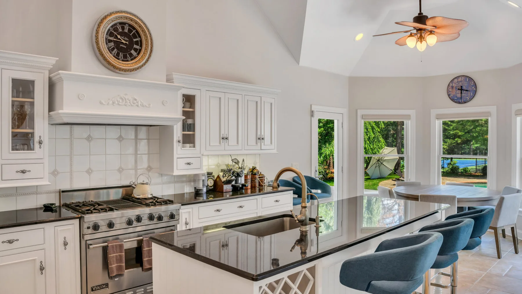 Una cocina luminosa con gabinetes blancos, una isla central y ventanas grandes.
